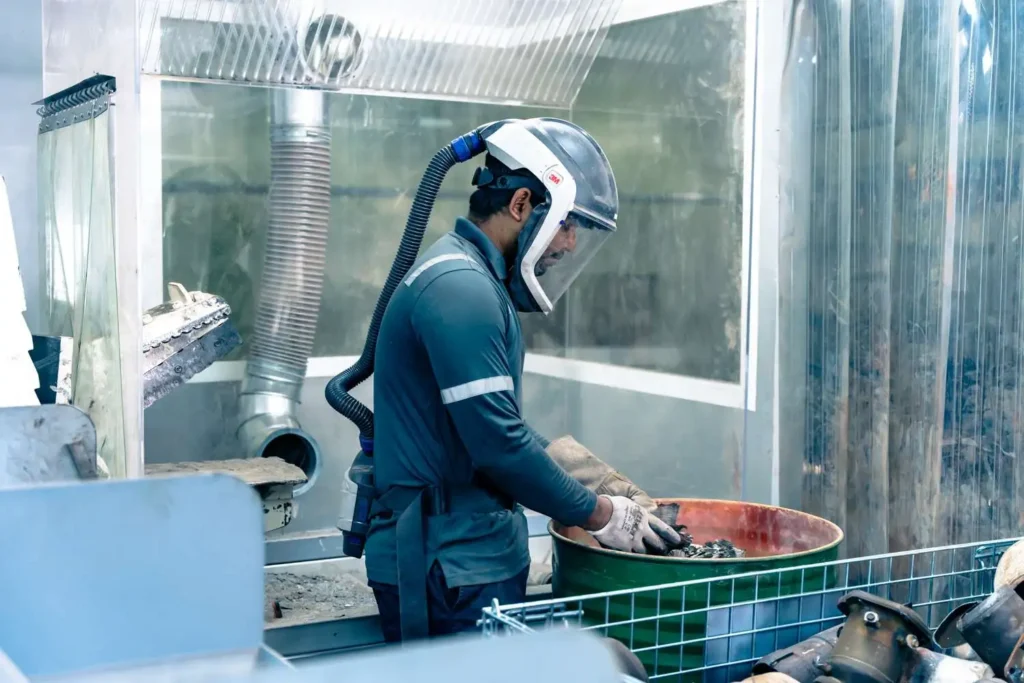 Technician in protective equipment handling catalyst material during converter processing