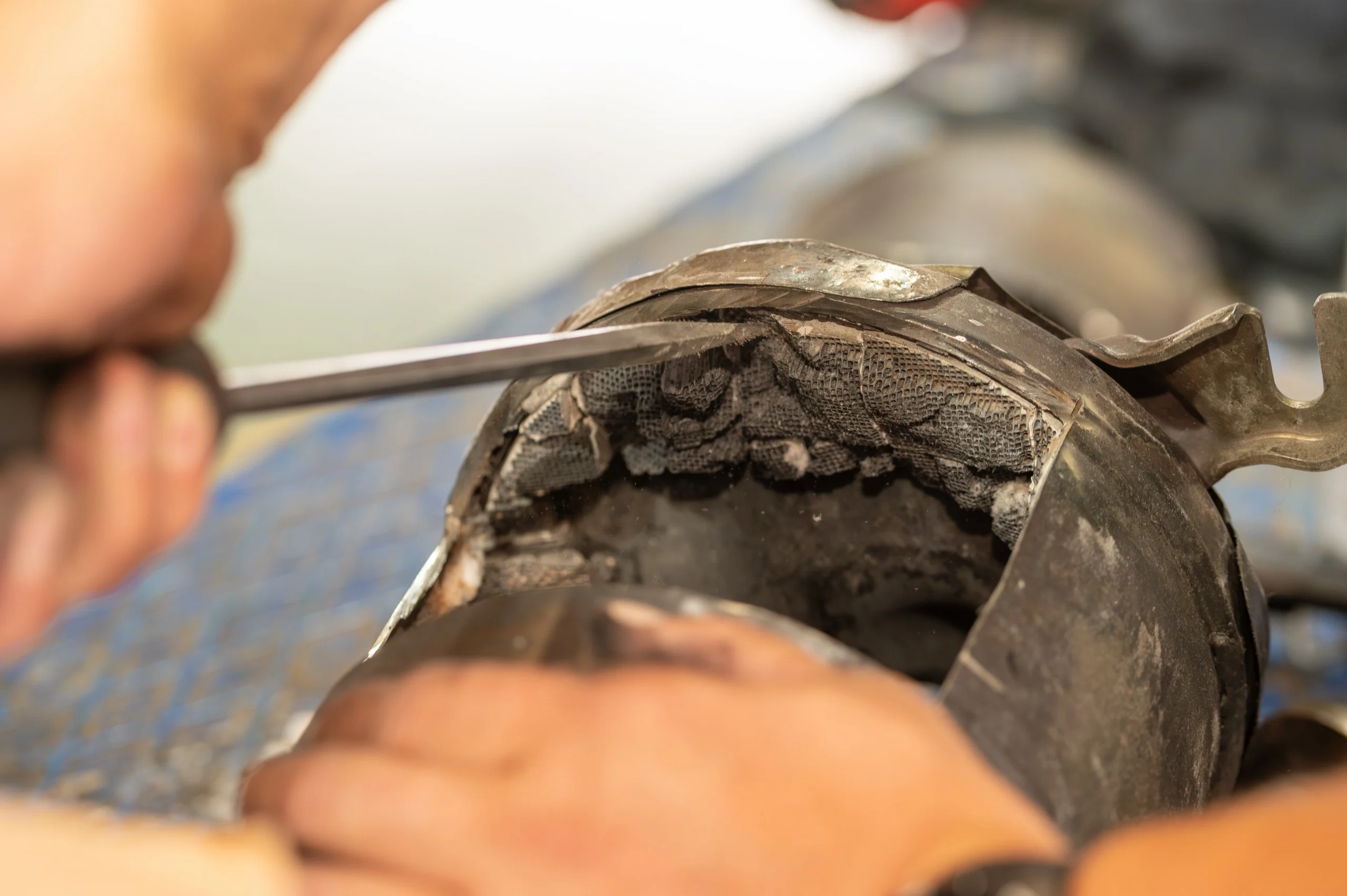 Mechanic prying open automotive catalytic converter casing for inspection